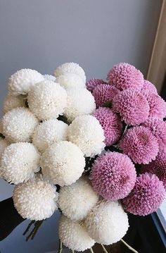 a bouquet of white and pink flowers sitting on top of a wooden table next to a window