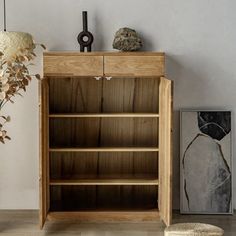 a wooden bookcase sitting on top of a hard wood floor next to a vase filled with flowers