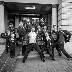 a group of men in suits and ties posing for a photo on the steps of a building