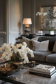 a living room filled with lots of furniture and flowers on top of a coffee table