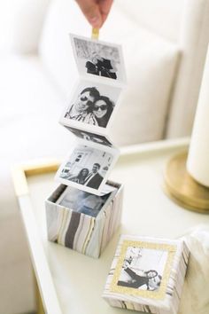 a person placing photos into a small box on a table next to a white couch