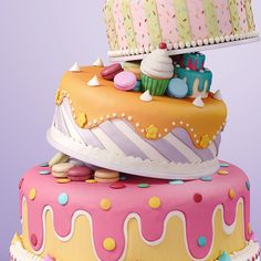 three tiered cake decorated with colorful icing and sprinkles on purple background