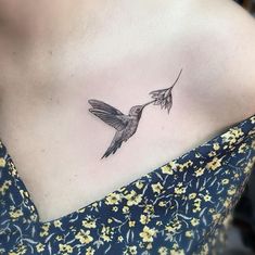 a small hummingbird tattoo on the back of a woman's shoulder and chest