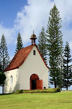 a white church with a red roof surrounded by trees