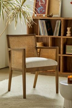 a wooden chair sitting on top of a white rug next to a potted plant