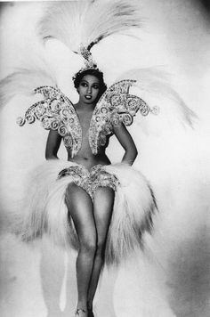 a black and white photo of a woman dressed in an angel costume with feathers on her head