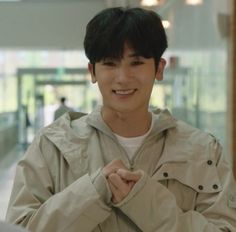 a young man standing in front of a glass wall with his hands on his chest