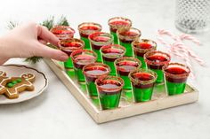 green glasses filled with red liquid and gingerbread cookies on a tray next to candy canes