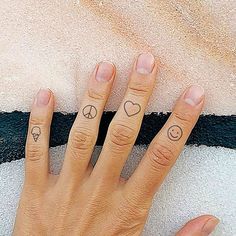 a woman's hand with two small tattoos on her fingers