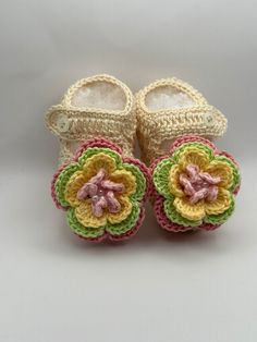 two crocheted baby shoes with flowers on them