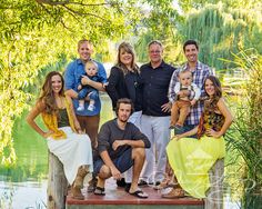 a group of people posing for a photo on a dock near the water and trees