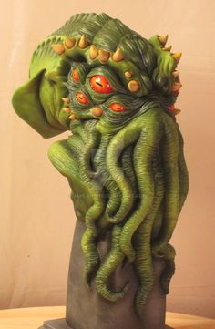 a green creature statue sitting on top of a wooden table