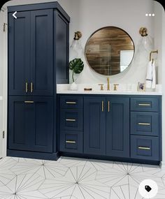 a bathroom with blue cabinets and a round mirror