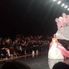 a woman is walking down the runway with balloons