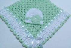 a green and white crocheted blanket with a hat on it's side