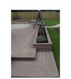 a wooden deck with planters on it and grass in the backround area