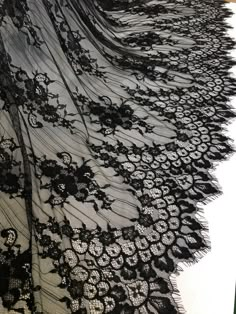 a black lace fabric with flowers and leaves on the edge is laying on top of a table