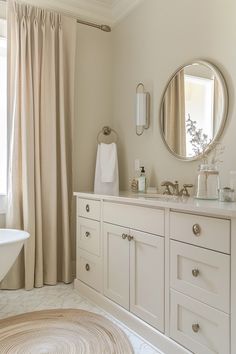 a bathroom with white cabinets and beige curtains