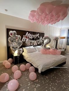 balloons are floating in the air above a bed with pink and silver decorations on it