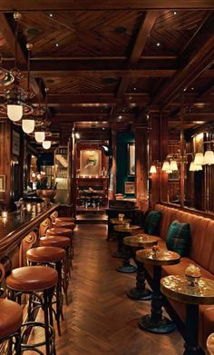 a restaurant with wooden tables and brown leather seats, bar stools and lights on the ceiling