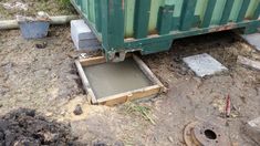 a dumpster sitting on the ground next to some concrete blocks and a metal container