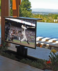 a baseball player swinging a bat on top of a flat screen tv in front of a crowd