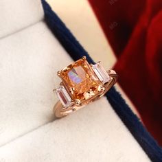 a fancy ring with an orange and white diamond in it's setting on a velvet box