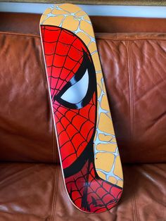 a skateboard with a spiderman face painted on it sitting on a leather couch