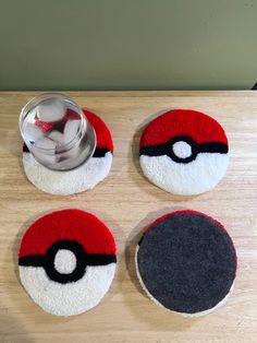 four coasters with different designs on them sitting on a wooden table next to a bowl