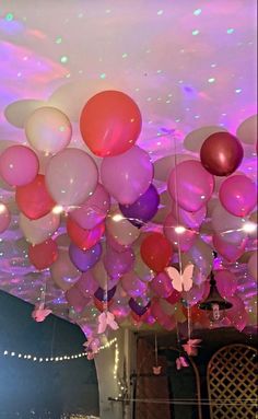 a room filled with lots of balloons floating in the air and butterflies on the ceiling