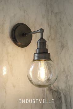 a light that is on the wall next to a marble counter top with words industvillee written below it