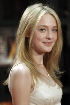 a woman with long blonde hair and blue eyes smiles at the camera while wearing a white dress