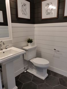 a white toilet sitting next to a sink in a bathroom under two framed pictures on the wall