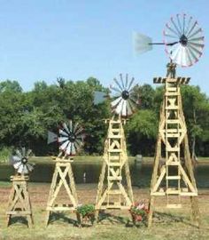 three wooden windmills sitting on top of a grass covered field