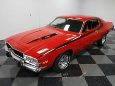 a red car is parked on a black and white checkered floor