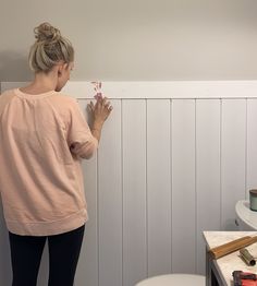 a woman standing in front of a white wall holding a toothbrush and looking at it