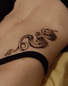 a woman's stomach with a dragon tattoo on the side of her body and an arm