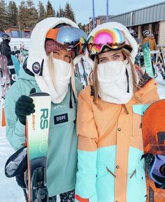 two people standing next to each other holding skis and snowboards in their hands