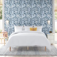 a bedroom with blue wallpaper and white bedding