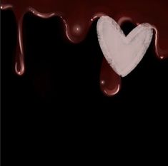 a heart shaped piece of paper sitting in the middle of melted chocolate on a black background