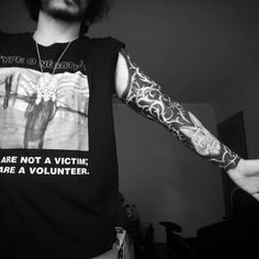 a man with tattoos on his arms and arm is wearing a t - shirt that says, are not a victim have a volunteer