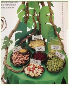 a table topped with bowls filled with different types of food next to green leafy branches