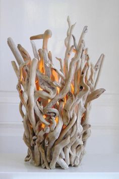 a sculpture made out of driftwood with fire in the middle and light coming from it