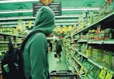 a person in a hooded sweatshirt is walking through a grocery store aisle