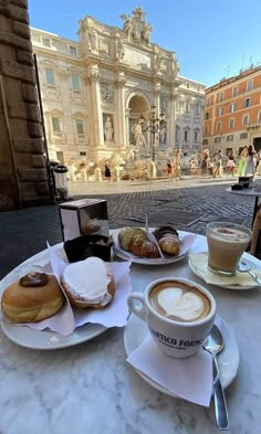 a table topped with plates of food next to a cup of cappuccino