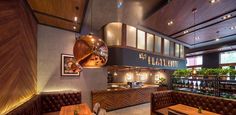 the interior of a restaurant with wooden tables and brown leather booths, potted plants on the wall