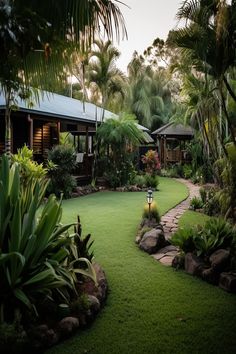 a lush green yard surrounded by trees and rocks with a pathway leading to the house