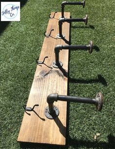 a row of metal pipes sitting on top of a wooden plank in the grass next to some water spigots