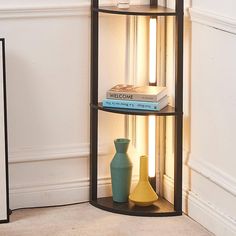 a corner shelf with books and vases on it in front of a white wall