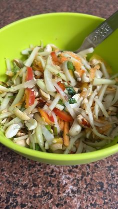 a green bowl filled with shredded vegetables on top of a granite counter next to a knife